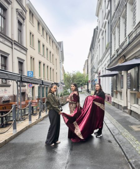 Drei Frauen auf der Luisenstraße. In der Mitte mit einem roten Samtkleid