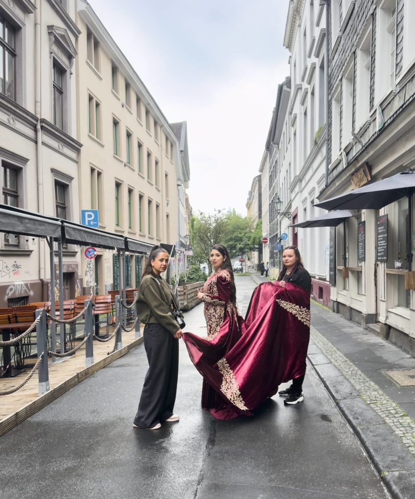 Drei Frauen auf der Luisenstraße. In der Mitte mit einem roten Samtkleid