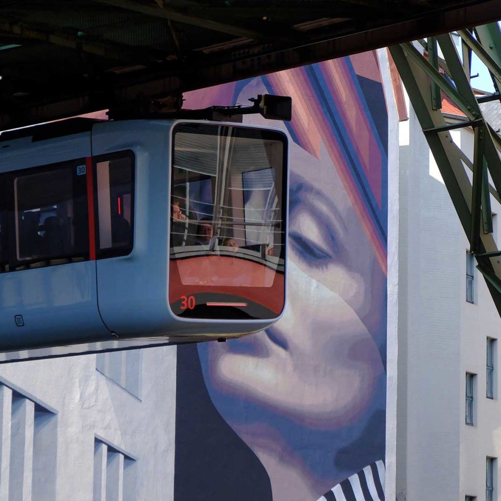 Schwebebahn vor einem Mural der Urban Art Galery