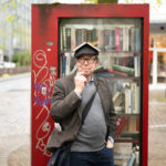Max Christian Graeff vor dem offenen Bücherschrank am Laurebtiusplatz
