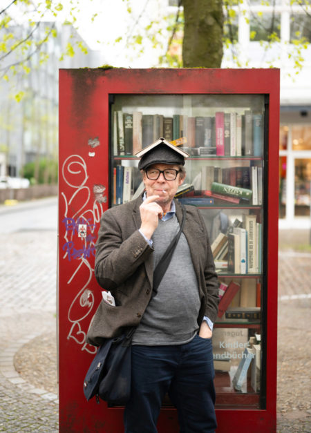 Max Christian Graeff vor dem offenen Bücherschrank am Laurebtiusplatz