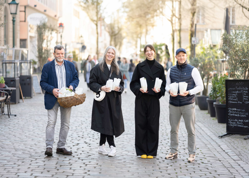 Team der IG Friedrich-Ebert-Straße verteilt Blumen auf dem Laurentiusplatz